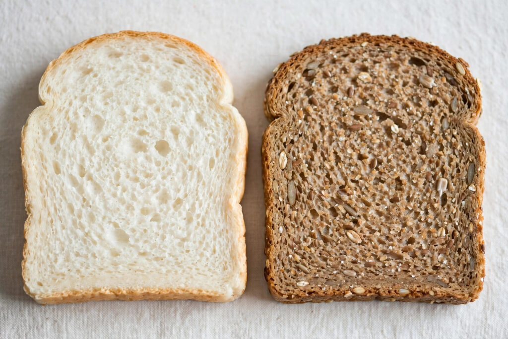 A slice of white bread next to a slice of brown wholemeal bread